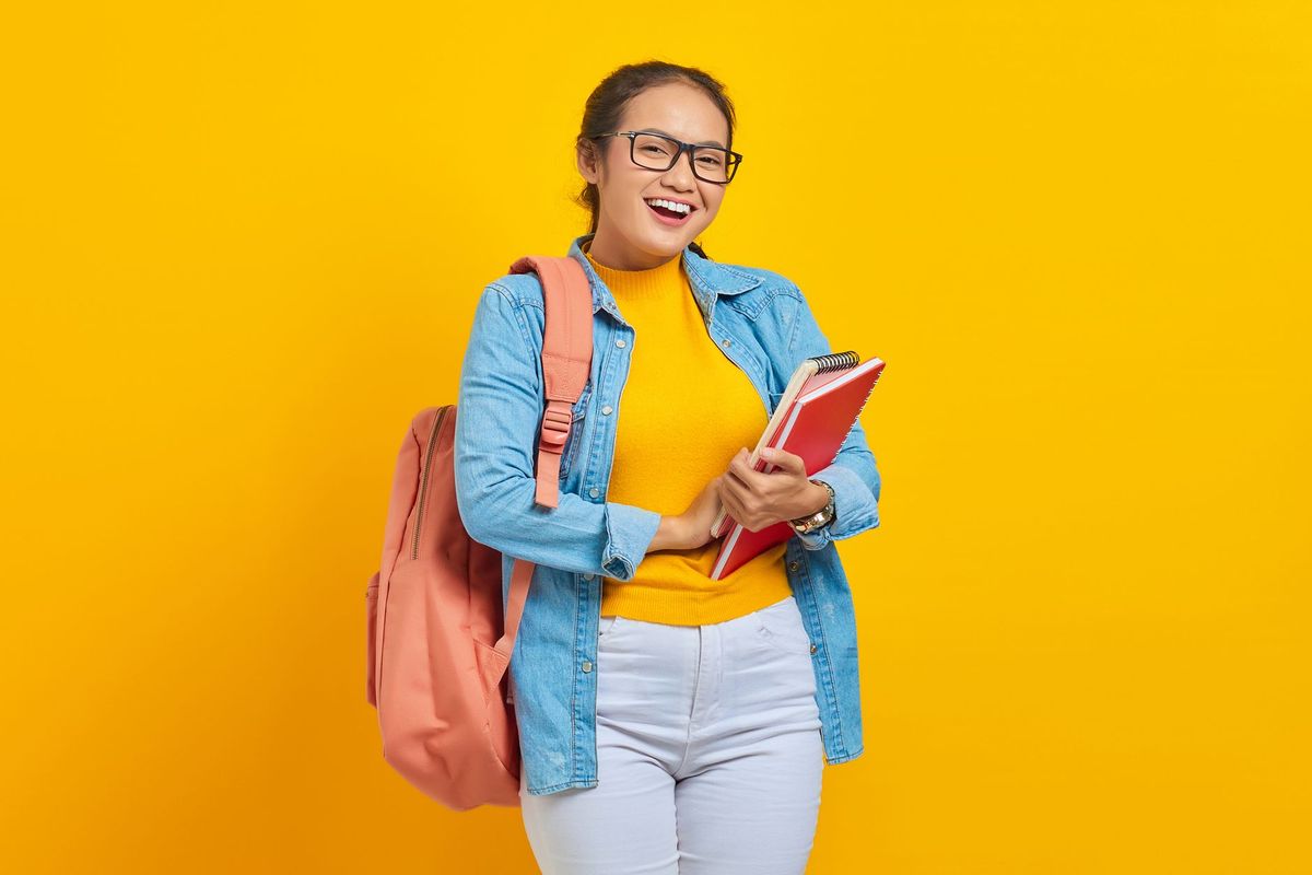 a happy teenage student studying with a notebook